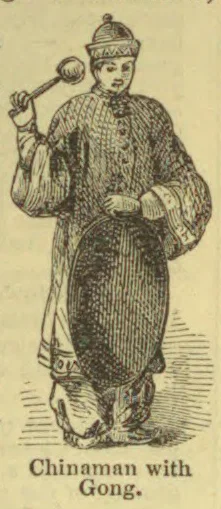 A man wearing a patterned robe and cap holds a gong mallet beside a gong.