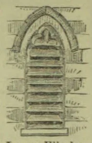 A pointed Gothic arch frames a tall opening fitted with horizontal louvered slats.