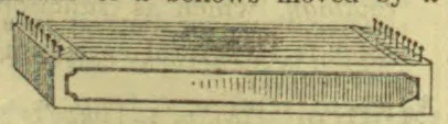 A long rectangular mechanical device with parallel grooves across its top and a row of narrow upright teeth or slots along its front.
