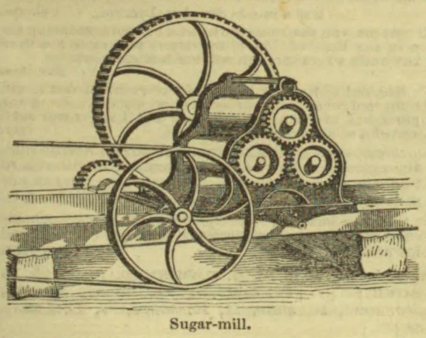 An antique sugar mill with large wheels and interlocking gears mounted on a wooden platform.