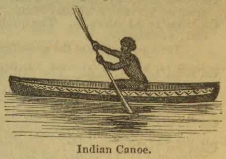 An Indigenous man paddles a decorated canoe across the water.