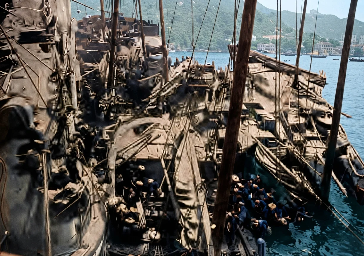Coaling H. M. S. "Terrible" in Hong Kong Harbor. Looking from the "Terrible" down into the Sampans and the crews at work. Great Britain once used her power to enforce the opium traffic. She is now aiding its suppression.
