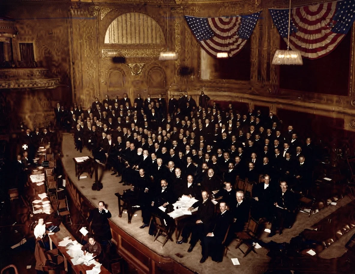Delegates to the "Inter-Church Conference on Federation," in Carnegie Hall, New York City, Nov. 15-21, 1905. They are seated on the large platform, by invitation, in order to get a better photograph. The SIGNS' special representative is directly under the white cross on the extreme left, at a reporter's table.