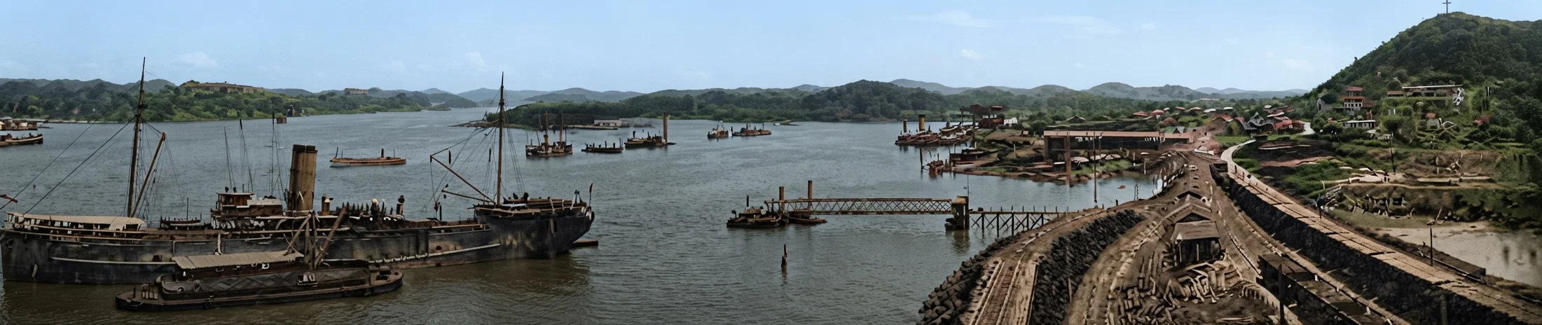 A bird's-eye view of Balboa and the Pacific coast entrance to Panama Canal, showing the canal entrance to the left, and a part of the American city of Balboa to the right. Beyond the hill, and under the cross, is the proposed location of a new chapel. A portion of the breakwater running out to the fortified island is in the immediate foreground to the right. This breakwater is largely made of rock taken from the Culebra Cut. The amount of rock and earth deposited in the cut in one slide would build a wall seven feet wide and seven high, extending from New York to San Francisco.
